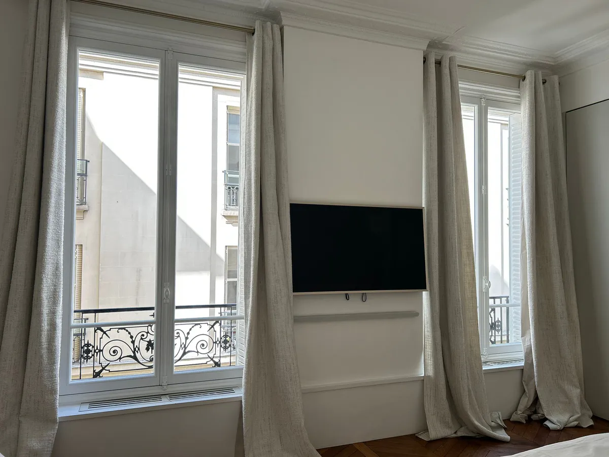 Chambre avec deux fenêtres en bois donnant sur un balcon