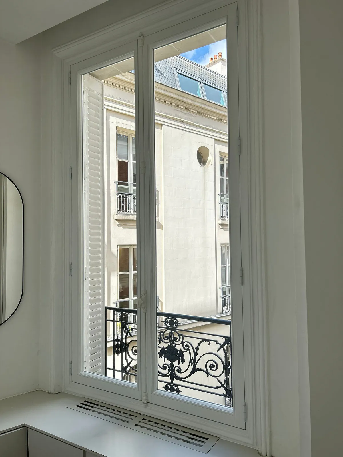 Fenêtre en bois donnant sur un balcon en fer forgé